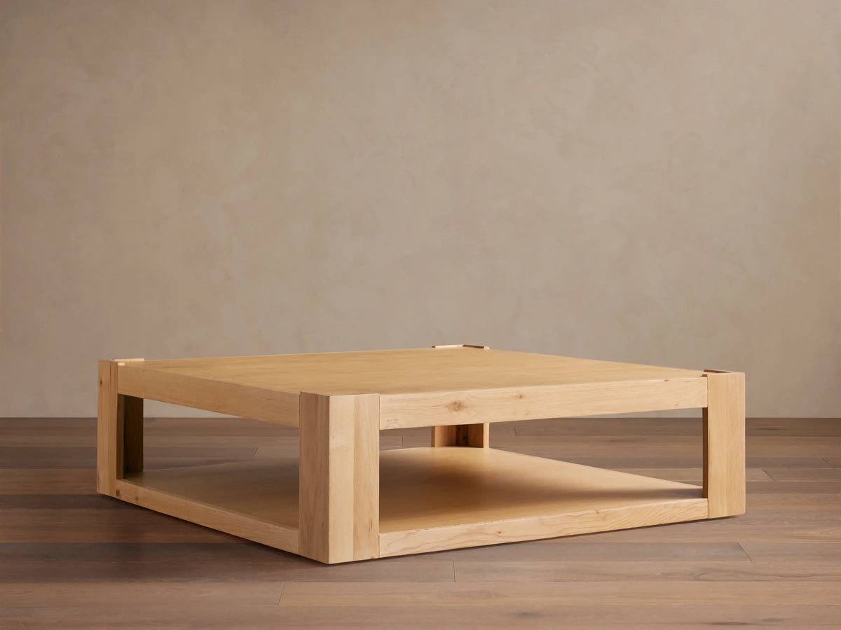 Devon Coffee Table, square natural oak wood. Features a thick top, sturdy square legs, and a practical lower storage shelf.