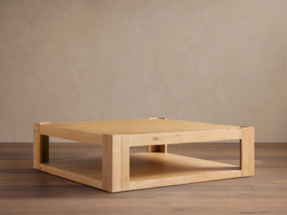 Devon Coffee Table, square natural oak wood. Features a thick top, sturdy square legs, and a practical lower storage shelf.