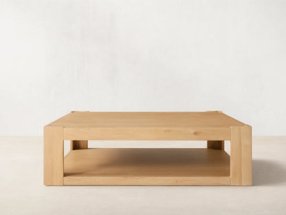Devon Coffee Table, square natural oak wood. Features a thick top, sturdy square legs, and a practical lower storage shelf.
