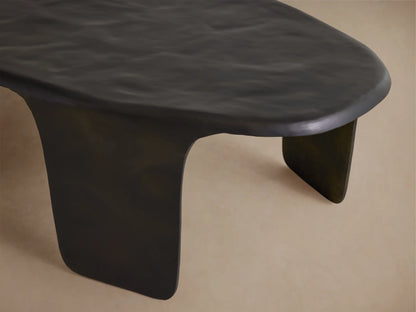 Dark bronze Melbourne Coffee Table, sculpted metal with organic wavy top & thick curved legs, on wood floor.
