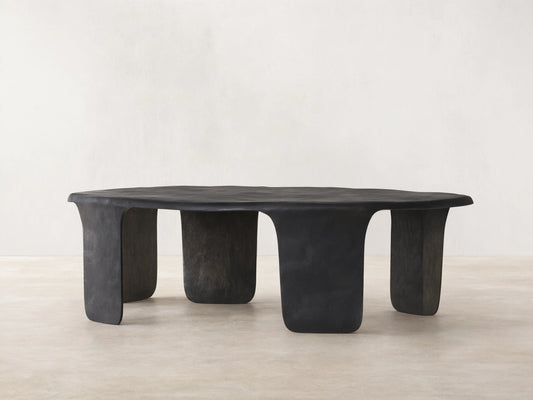 Melbourne Coffee Table, dark bronze metal, featuring an organic, wavy top and thick, sculpted legs on a wooden floor.