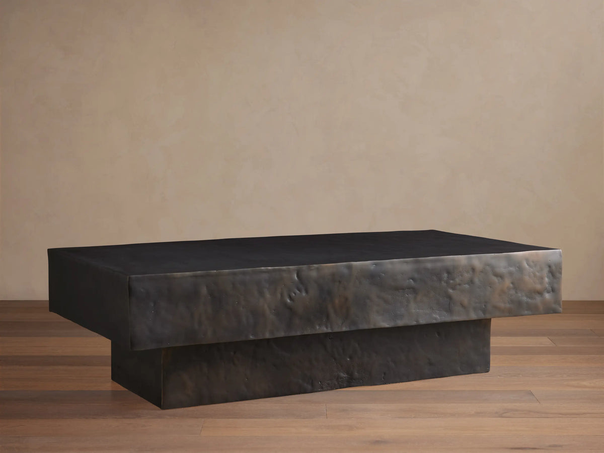 Sydney Coffee Table in a minimalist design, featuring a rectangular shape with a dark, textured finish, set on a hardwood floor.