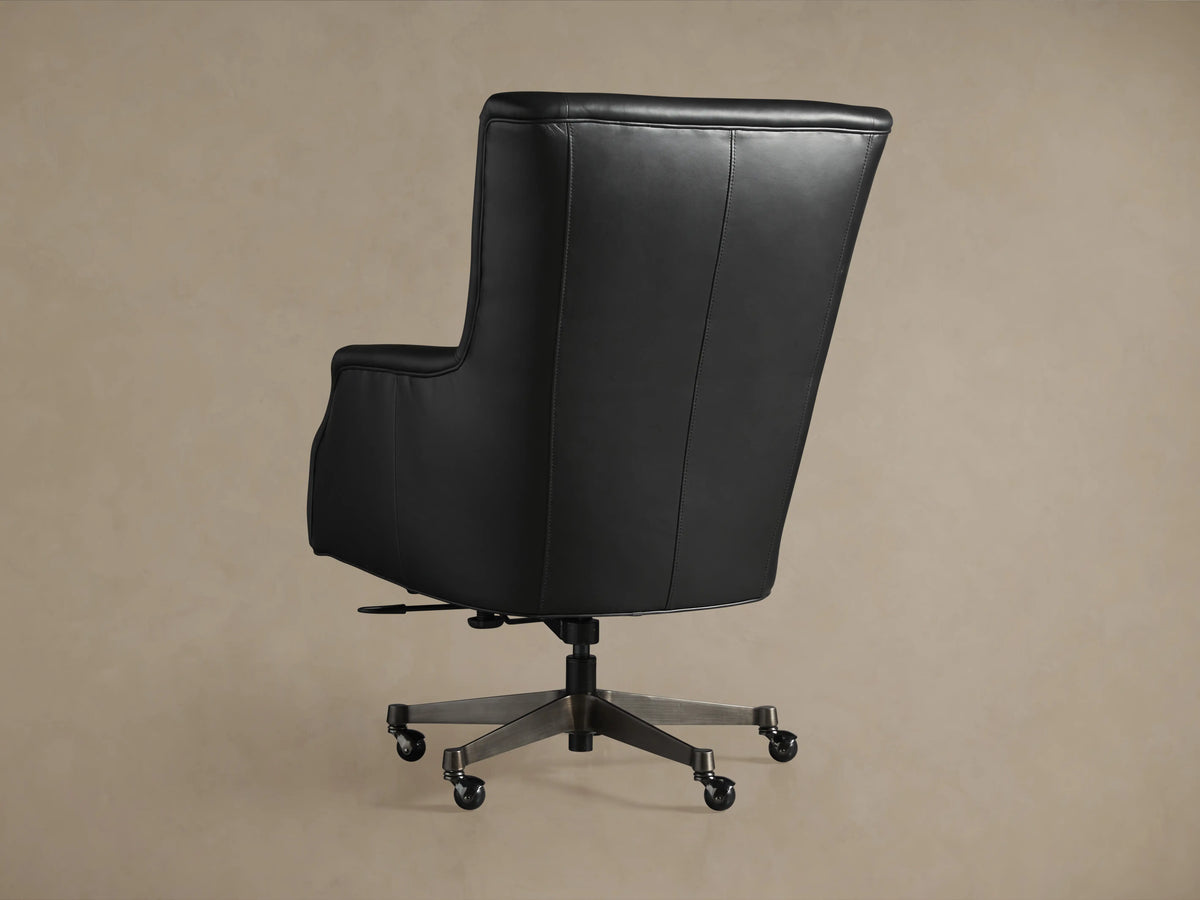 Back view of the Alex Leather Desk Chair, featuring sleek black leather upholstery, hand-applied nailhead trim, and a sturdy metal base with caster wheels.