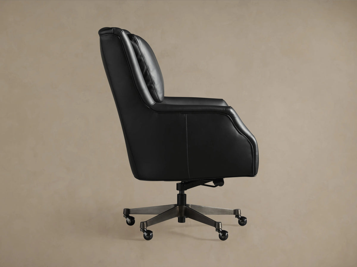 Alex Leather Desk Chair in black, side view showing curved back, padded seat, and armrest. It features a five-wheel base.
