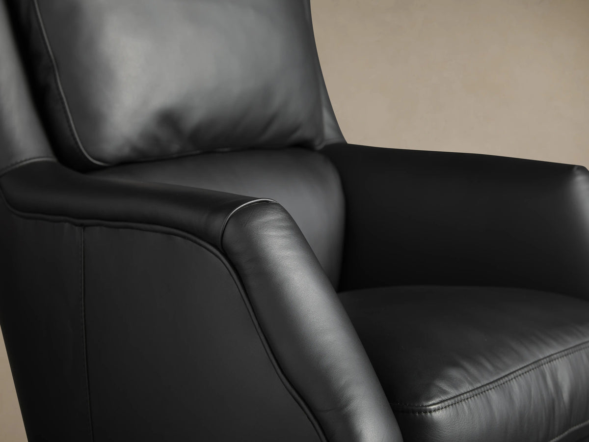 Black leather desk chair featuring smooth upholstery and hand-applied nailhead trim. Armrests and backrest provide a sleek, modern look.