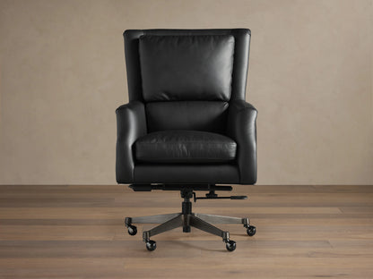 Black leather desk chair on a wooden floor, featuring cushioned seat and back, adjustable base with wheels, and nailhead trim.
