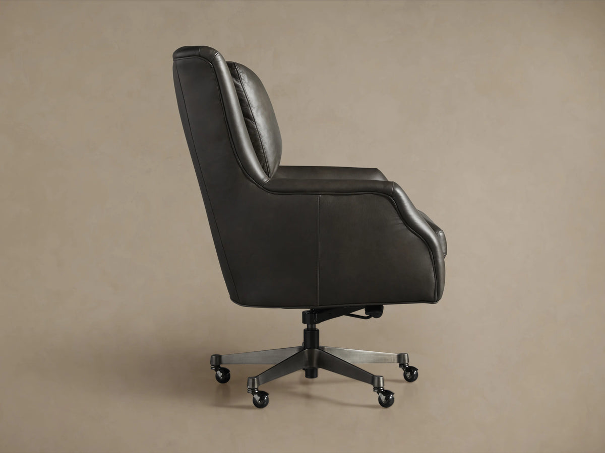 Close-up of Alex Leather Desk Chair in dark grey, featuring soft leather armrest with silver piping, seat, and cushioned back.