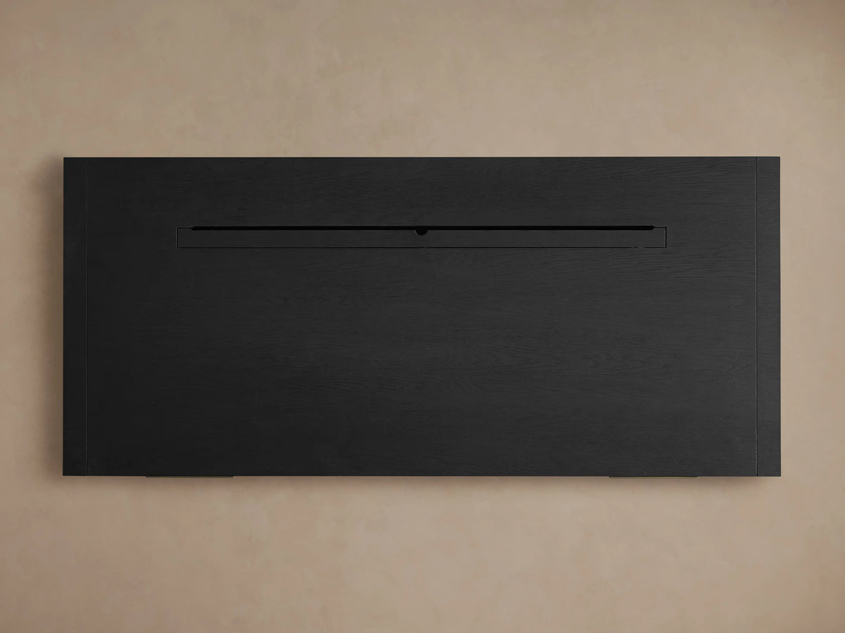 Dark black Bodhi Executive Desk, wire-brushed oak texture, featuring a wide open central shelf, against a beige wall.