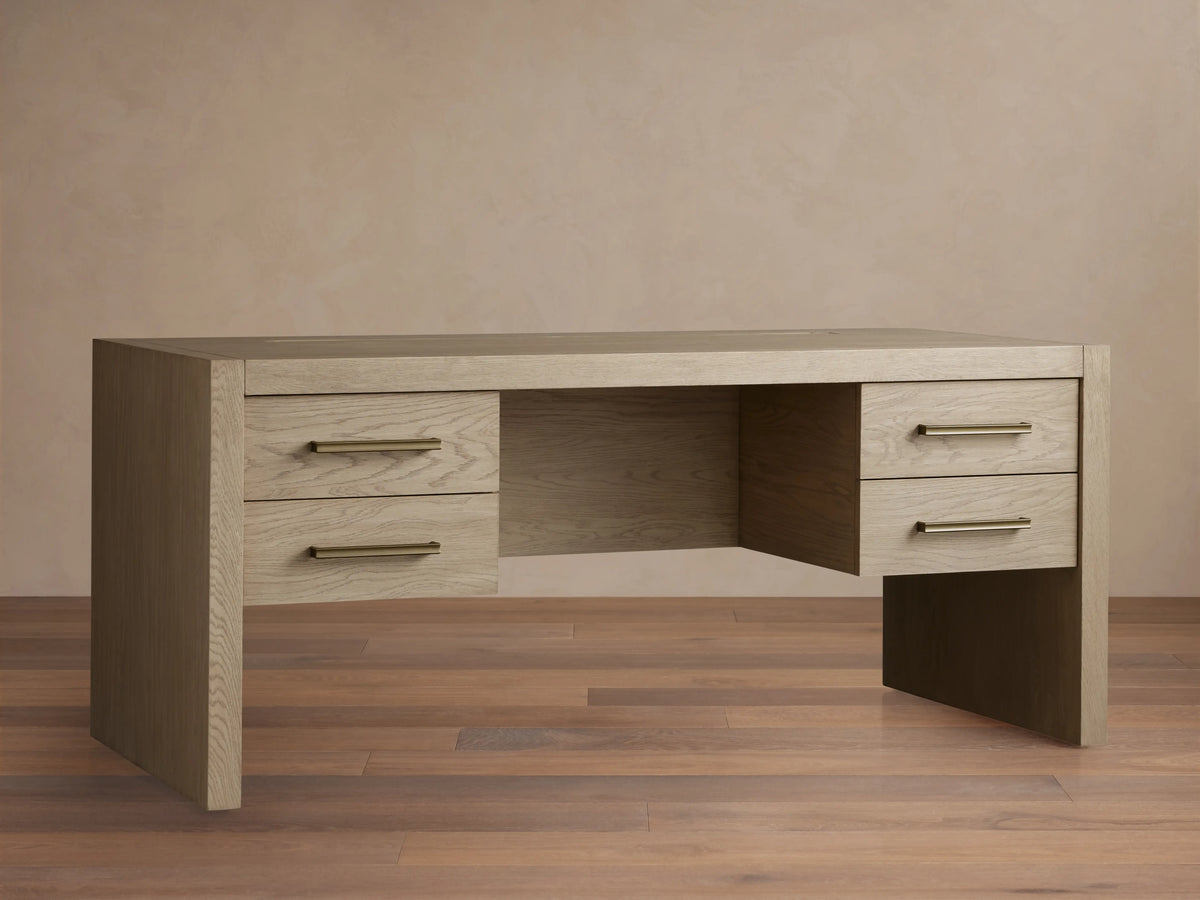 Bodhi Executive Desk, light wire-brushed white oak with an aged look, 4 drawers & horizontal brass pulls, front view.
