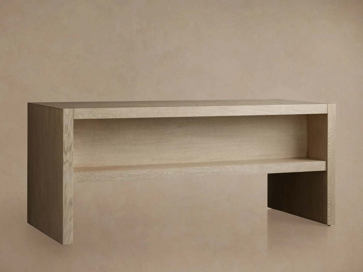 Close-up, angled view of the Bodhi Executive Desk's light wire-brushed white oak top, showing grain and a narrow cord management slot.