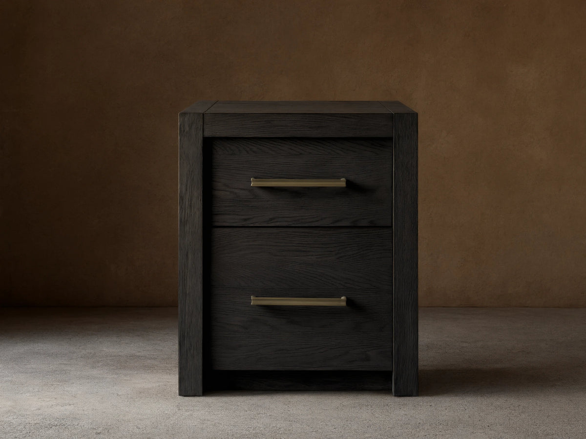 Bodhi Modular File in black oak, featuring two drawers with brass pulls on a wood floor. The design is simple and modern.