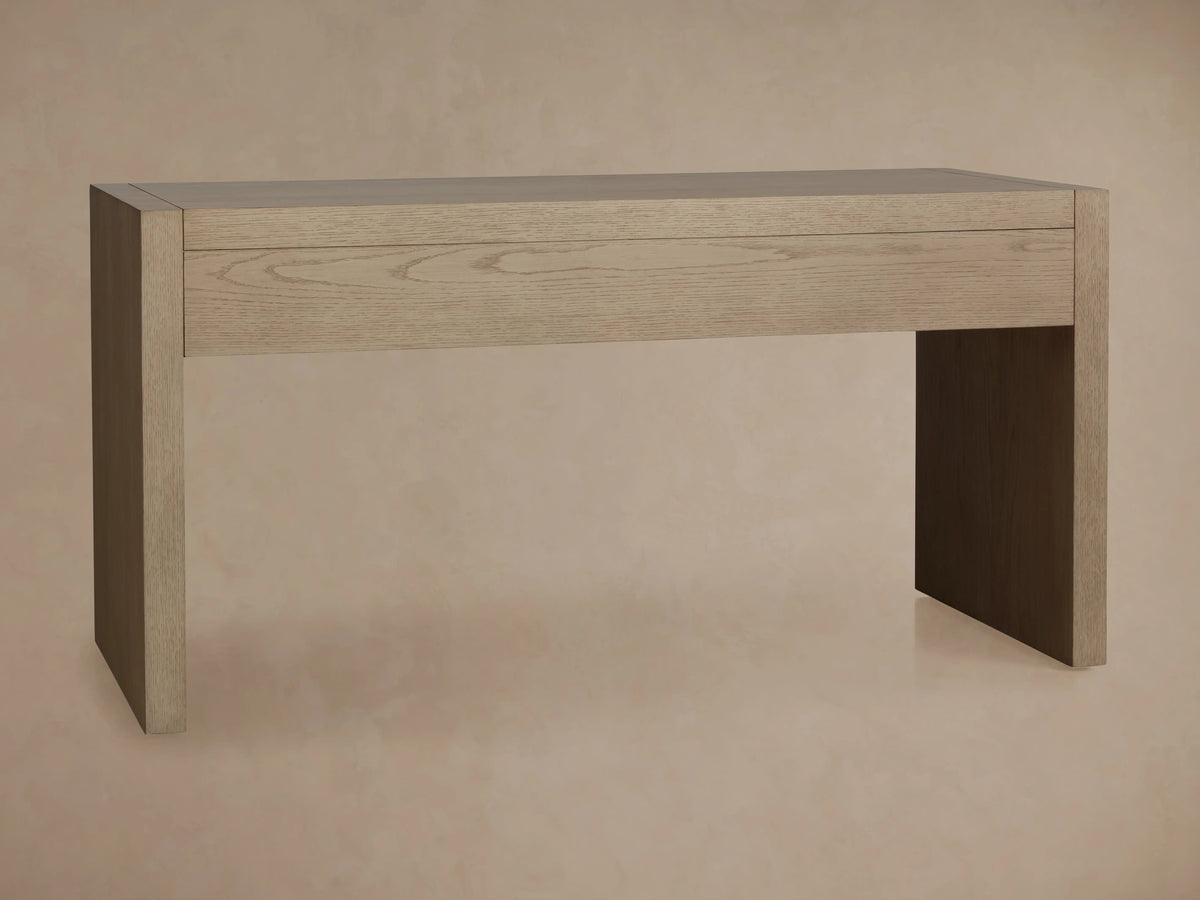 Bodhi Writing Desk, made from light wire-brushed white oak, featuring a wide integrated drawer and two solid panel legs.