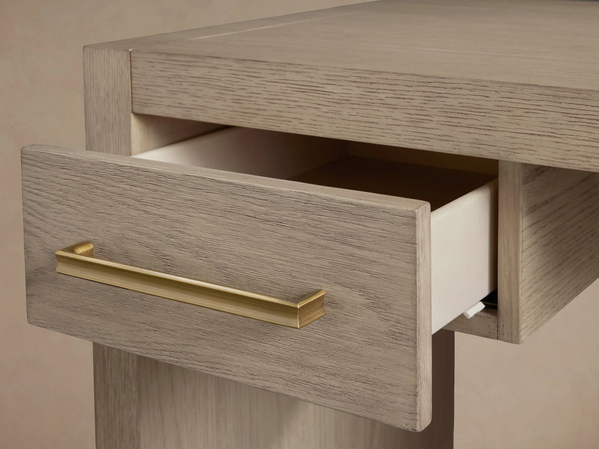 Bodhi Writing Desk, handcrafted light gray-brown wire-brushed white oak desk with two drawers and brass pulls, front view.