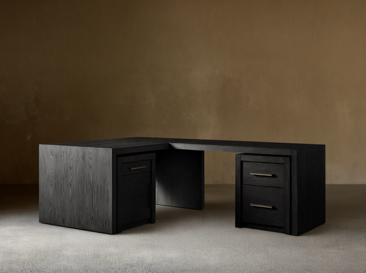 Bodhi Modular Desk, L-shaped, dark wire-brushed oak, 3 drawers with brass pulls, on wooden floor against a tan wall.