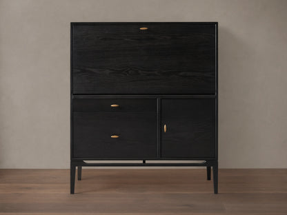Dark ash wood Brock Hideaway Desk with a fold-down front, two drawers, and a side cabinet, featuring gold handles.