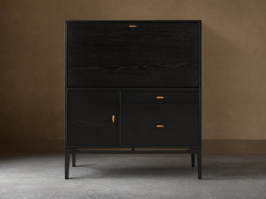 Dark ash wood Brock Hideaway Desk with a fold-down front, two drawers, and a side cabinet, featuring gold handles.