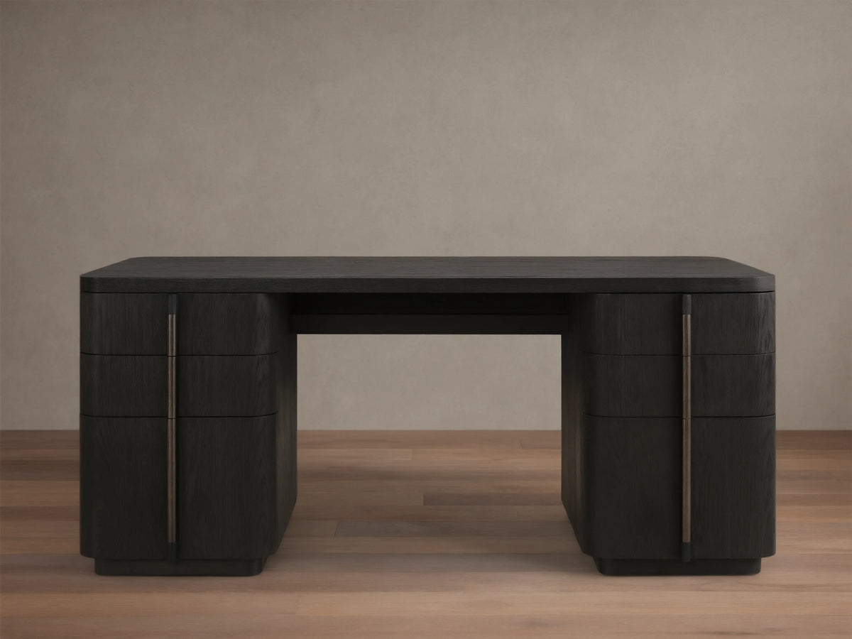 Front view of a dark wood finish writing desk with rounded corners and six drawers featuring long, vertical bronze-toned pulls.