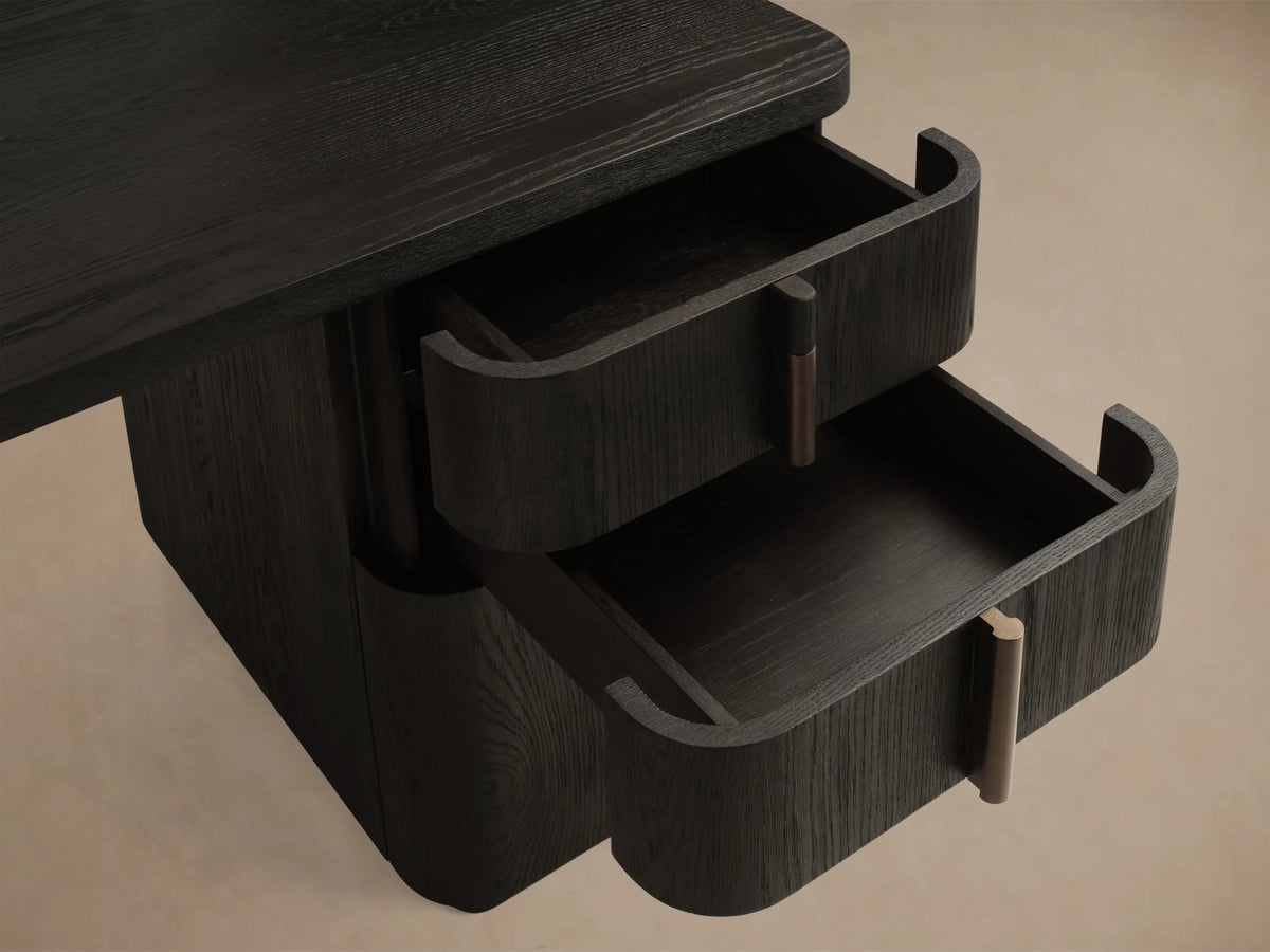 Front view of a dark wood desk with two pedestals, each containing three drawers and vertical dark pulls. It has rounded edges.