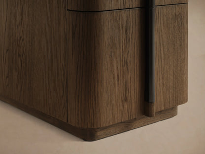 Close-up of a rich brown wood cabinet with an open drawer, curved front, and black vertical handle.