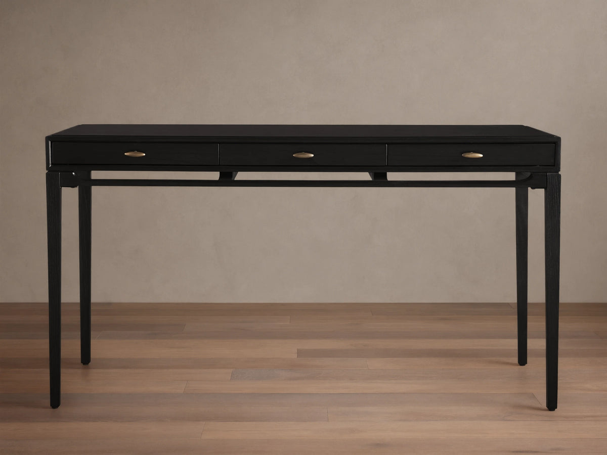 Brock Writing Desk with black finish, solid ash wood, three drawers with brass handles, and a leather writing surface.