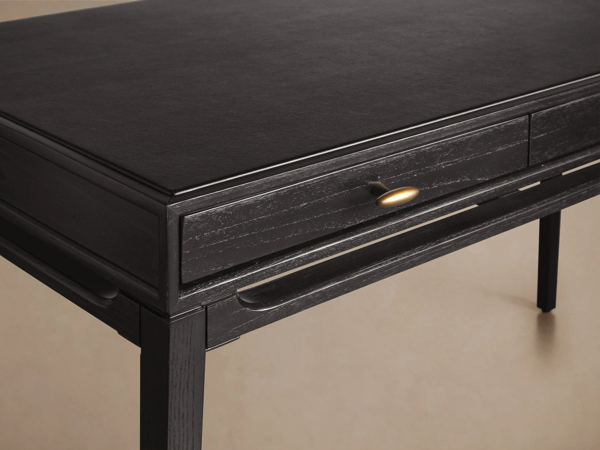 Brock Writing Desk crafted from dark ash wood with a smooth black leather writing surface, featuring a subtle sheen and a single drawer.