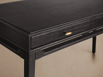 Brock Writing Desk crafted from dark ash wood with a smooth black leather writing surface, featuring a subtle sheen and a single drawer.