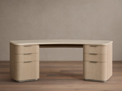 Caden Executive Desk. Light sand wood with rounded edges, cream marble top, and six drawers with brushed nickel hardware.