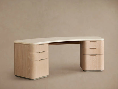 Caden Executive Desk. Light sand wood with rounded edges, cream marble top, and six drawers with brushed nickel hardware.