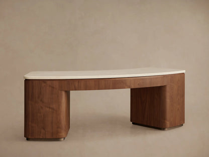 Close-up of Caden Executive Desk. Walnut wood base with curved front, cream marble top. Lower drawer partially open, bronze handle.