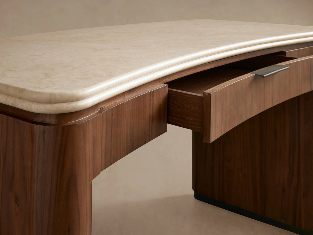 Caden Writing Desk in dark walnut wood with curved legs and a cream marble top, featuring a central drawer with a pull.