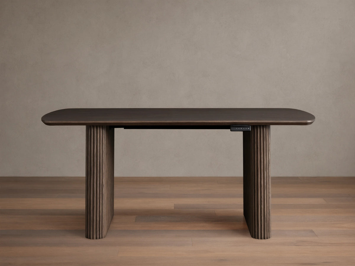 Front view of the dark brown red oak Camonte Lift Desk with a rounded rectangular top, vertically ribbed legs, and a control panel.