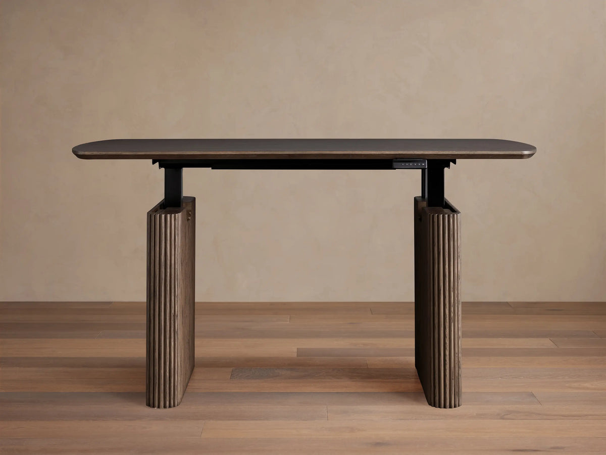 Front view of the dark brown red oak Camonte Lift Desk with a rounded rectangular top, vertically ribbed legs, and a control panel.