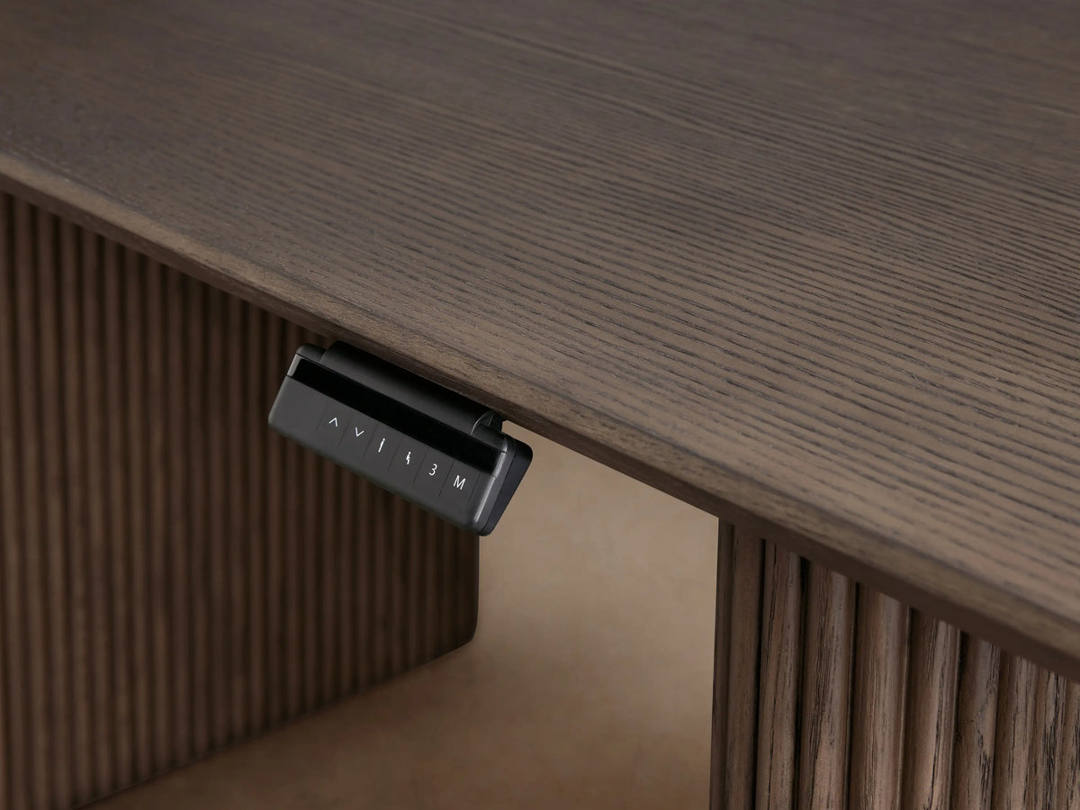 Front view of the dark stained red oak Camonte Lift Desk with fluted legs and a control panel on the right underside.