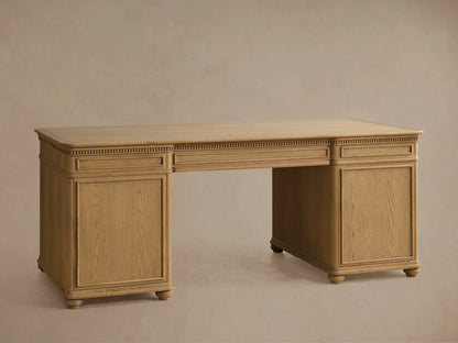Close-up of Carlisle Executive Desk in light oak wood, angled view. Top drawer closed, middle partially open, bottom fully open with filing rails. Dentil molding, antique brass pulls.