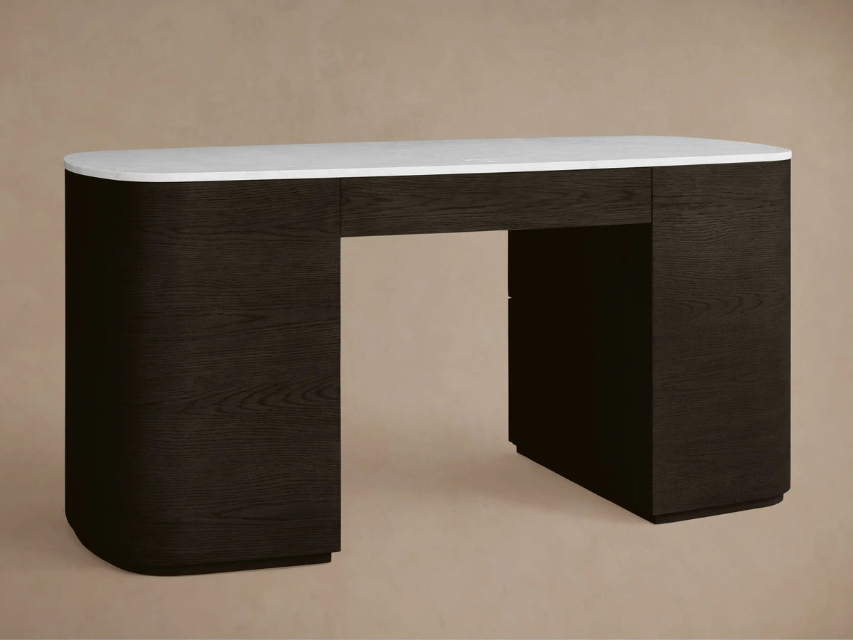 Close-up of the Danny Executive Desk, showing its white Carrara marble top, dark wood, gold handles, and a partially open curved drawer.