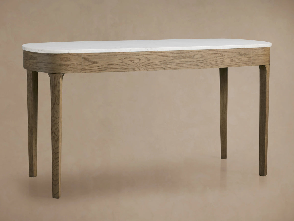 Danny Writing Desk: fawn oak veneer, oval white Carrara marble top, two drawers with brass handles. Front view on wood floor.