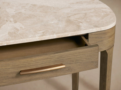 Close-up of Danny Writing Desk: earth-toned marble top, fawn oak veneer body, partially open drawer with brass handle.