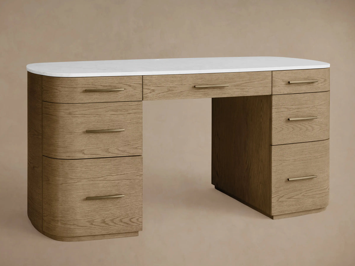 Danny Executive Desk, fawn oak veneer with rounded edges, white marble top, 7 drawers with brass bar handles, on wood floor.
