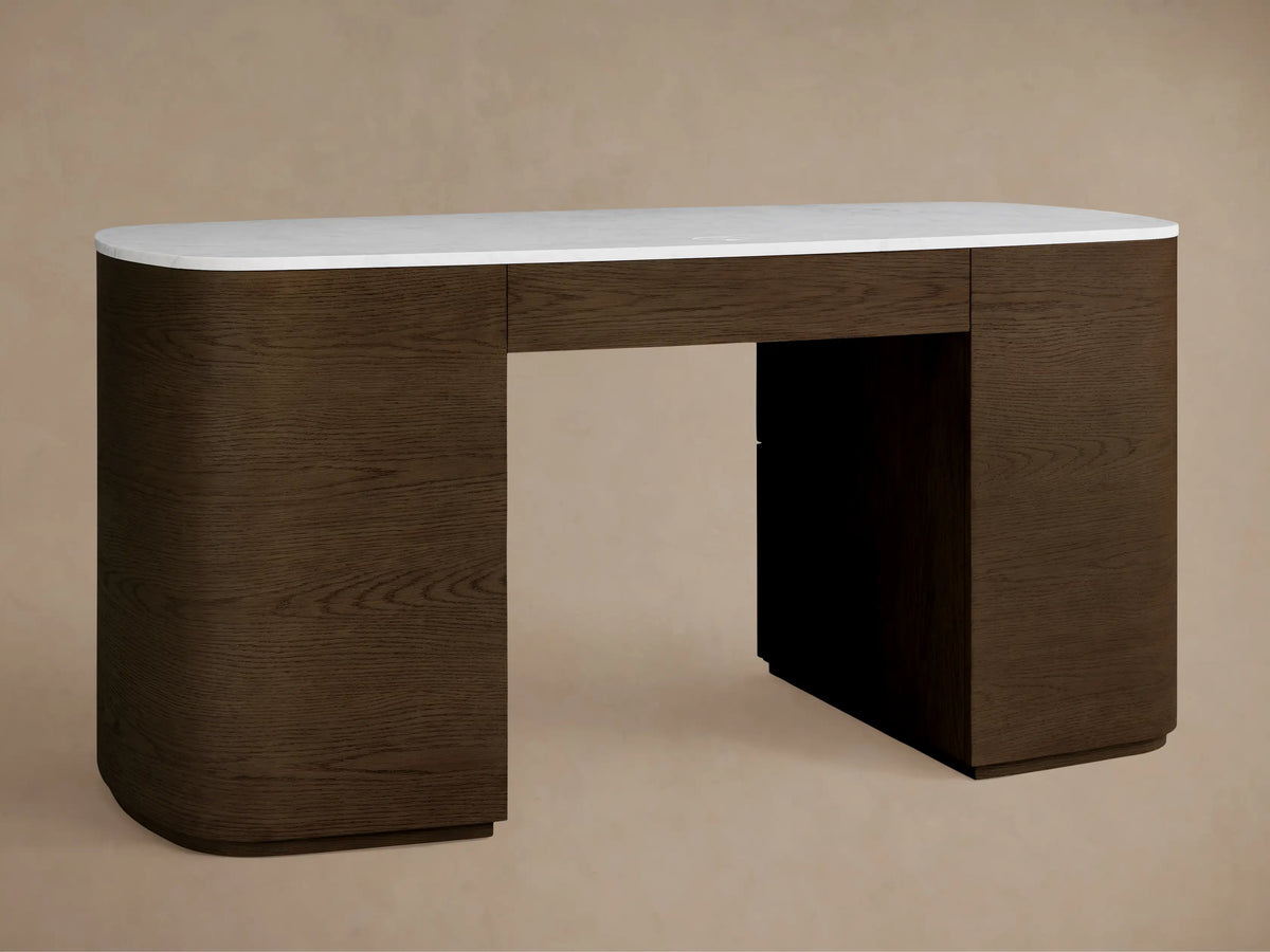 Close-up, angled view of the Danny Executive Desk. White Carrara marble top, dark brown oak veneer body, partially open drawer with gold pulls.