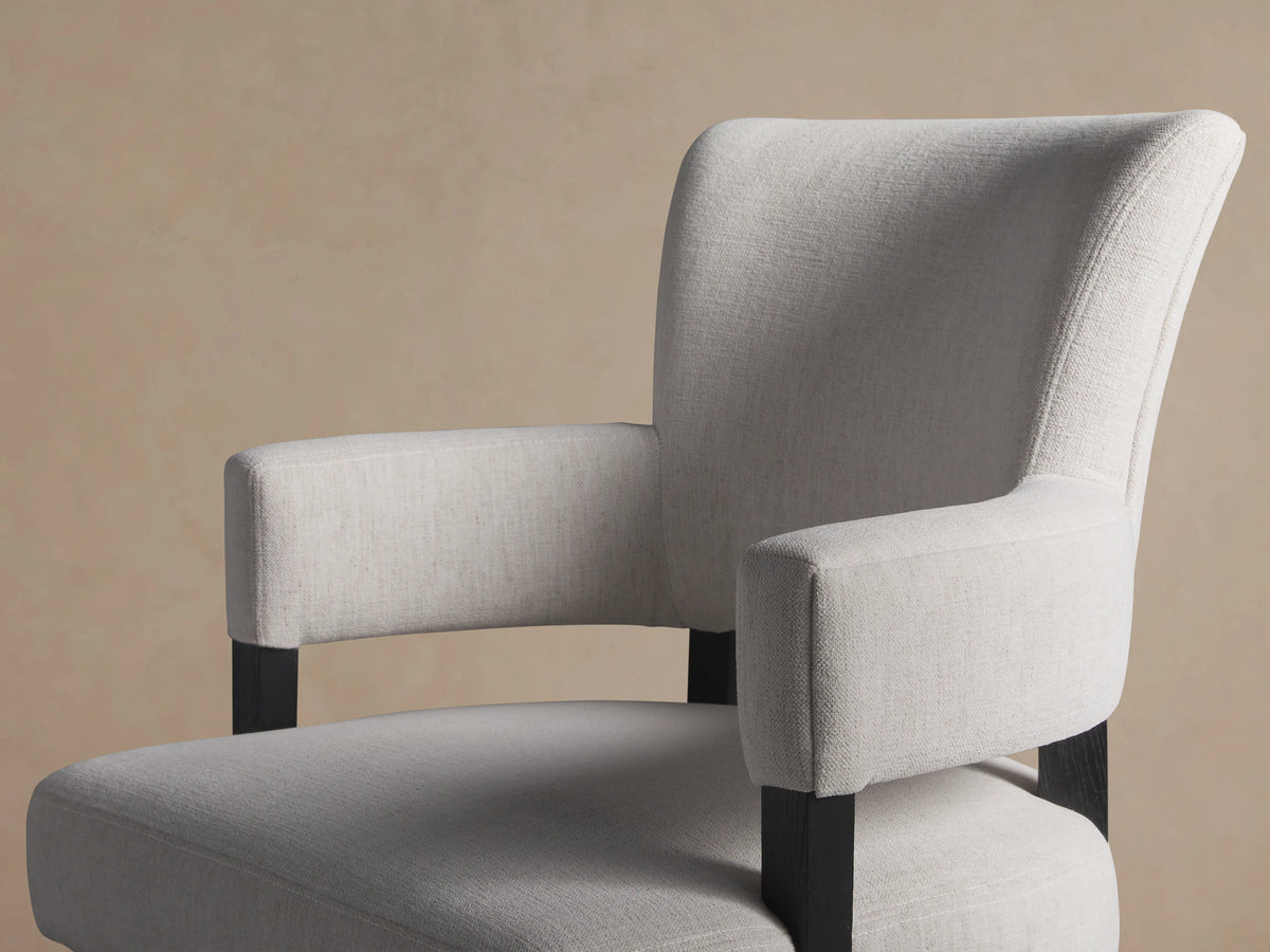 Light grey Fallyn Desk Chair with padded armrests and backrest on a metal swivel base with five wheels, set on a wooden floor.