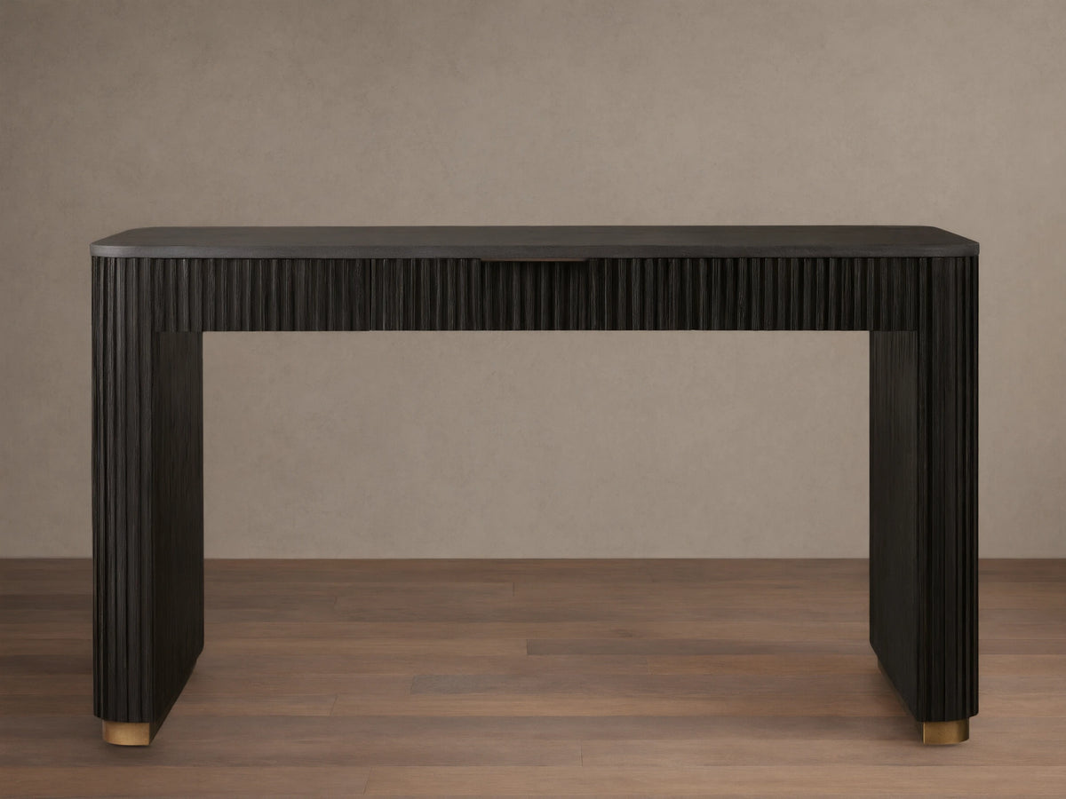Finnley Writing Desk in dark wood finish, featuring reeded texture, light brass drawer pull, and gold-accented feet on a wooden floor.