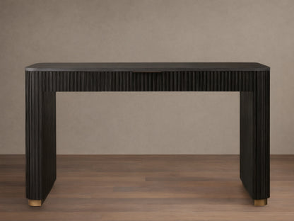 Finnley Writing Desk in dark wood finish, featuring reeded texture, light brass drawer pull, and gold-accented feet on a wooden floor.