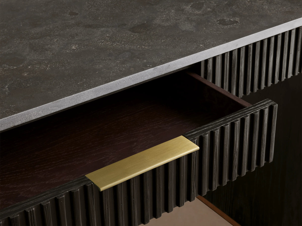 Finnley Writing Desk in Ebony finish, features reeded wood texture, central drawer with brass pull, set on wooden floor.