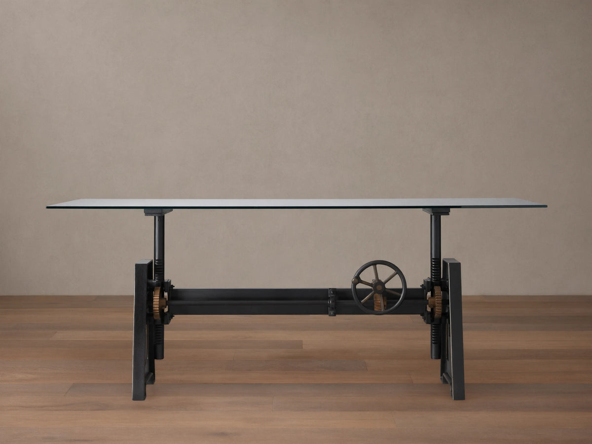 Industrial Crank Desk with a sleek glass top, supported by a sturdy black rubbed copper base and visible crank mechanism.