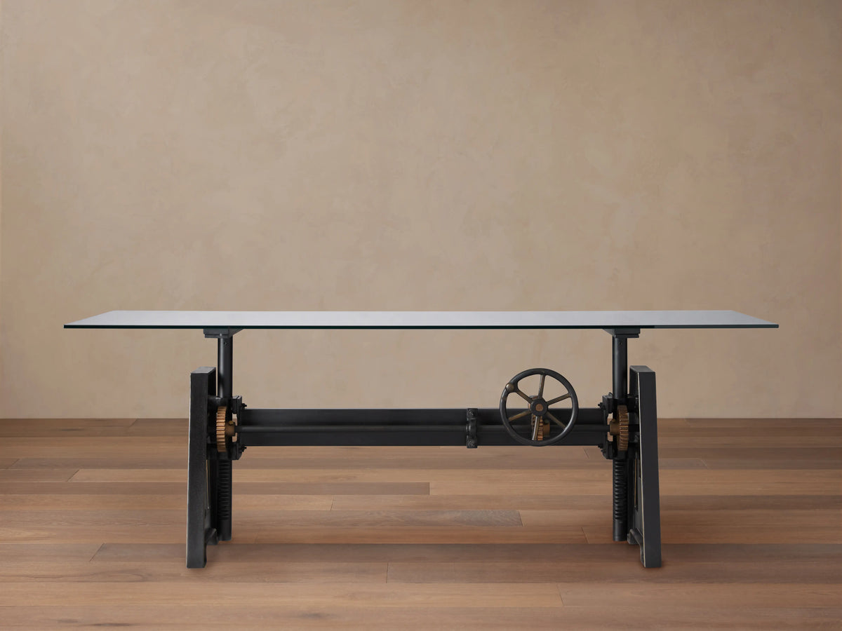 Industrial Crank Desk with a sleek glass top, supported by a sturdy black rubbed copper base and visible crank mechanism.