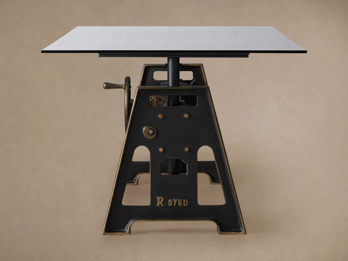Industrial Crank Desk's glass top with black rubbed copper base, showing crank mechanism and gears on the side.