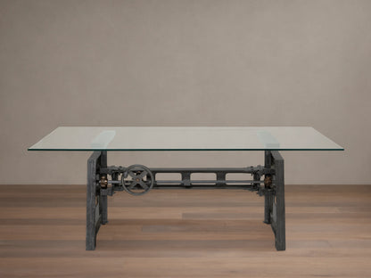 Industrial Crank Desk with clear rectangular glass top, dark metal base featuring a prominent crank wheel, on a wooden floor.