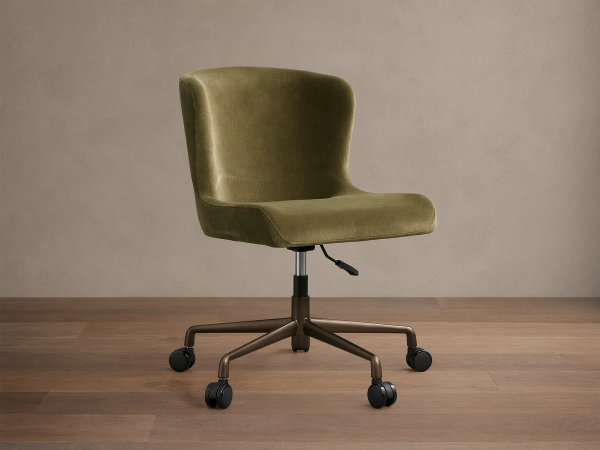 Kirsten Desk Chair, green velvet upholstery with a curved back, on a dark brown powder-coated aluminum base with 5 casters.