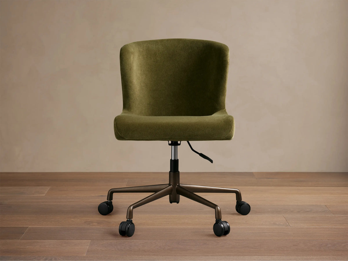 Kirsten Desk Chair, green velvet upholstery with a curved back, on a dark brown powder-coated aluminum base with 5 casters.