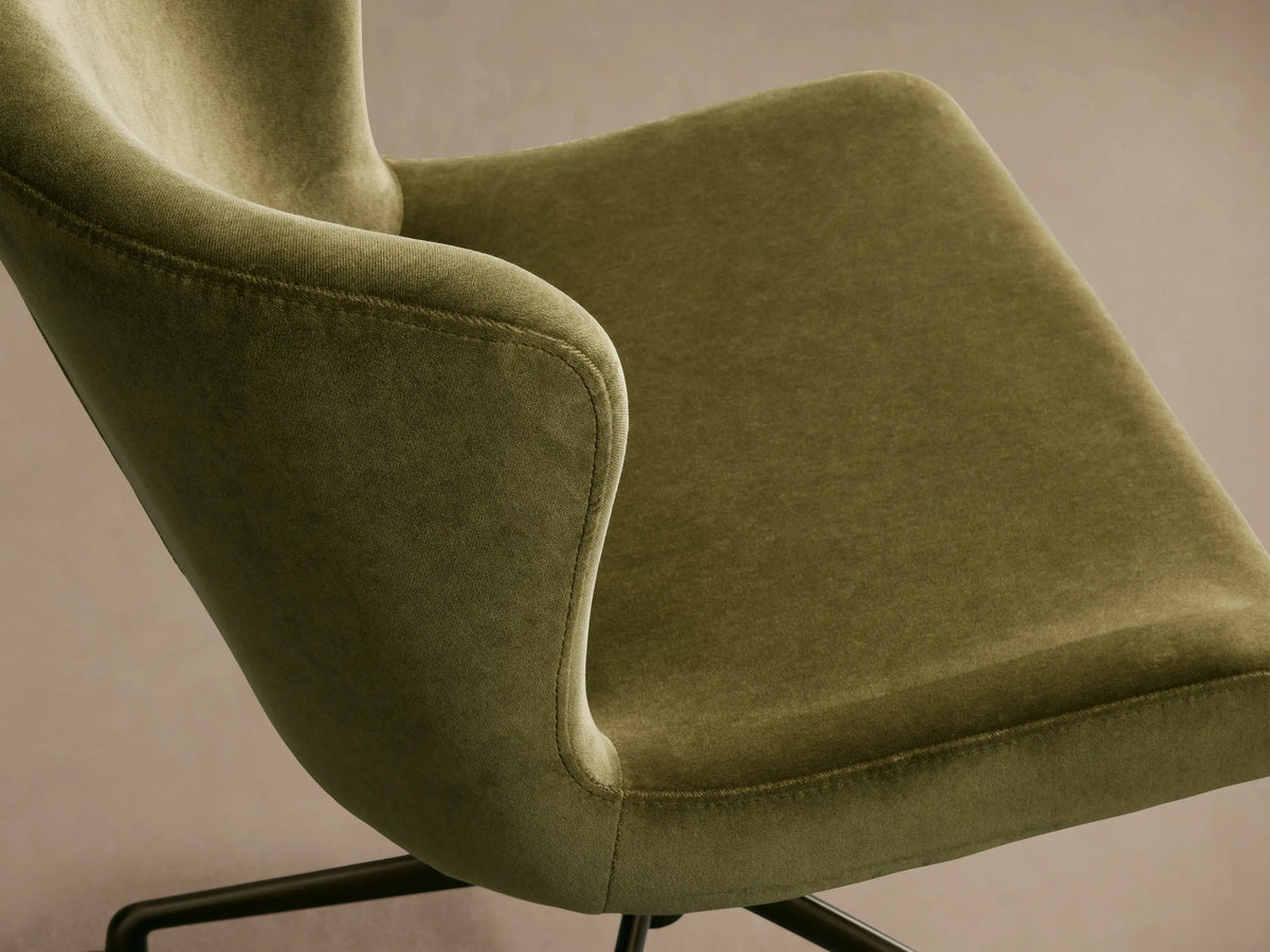 Kirsten Desk Chair with olive green velvet upholstery, bronze swivel base, and five casters, front view on a wooden floor.